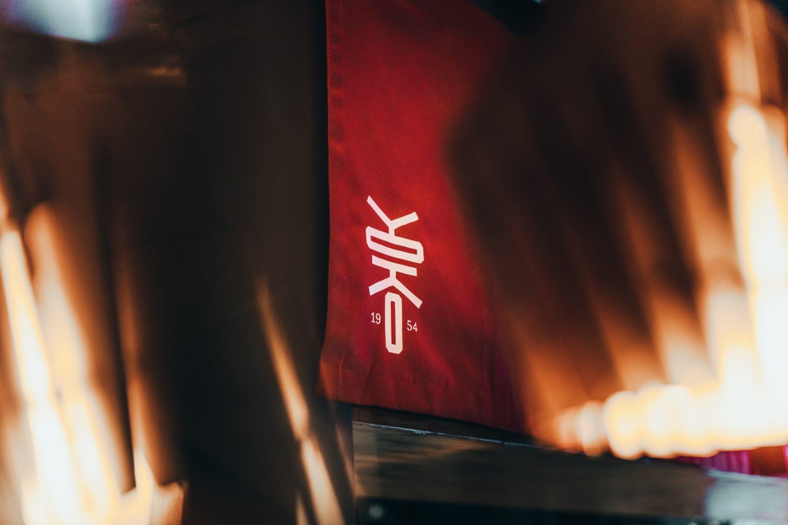 Nahaufnahme eines roten japanischen Vorhangs mit dem weißen Logo des Restaurants Yoko.
